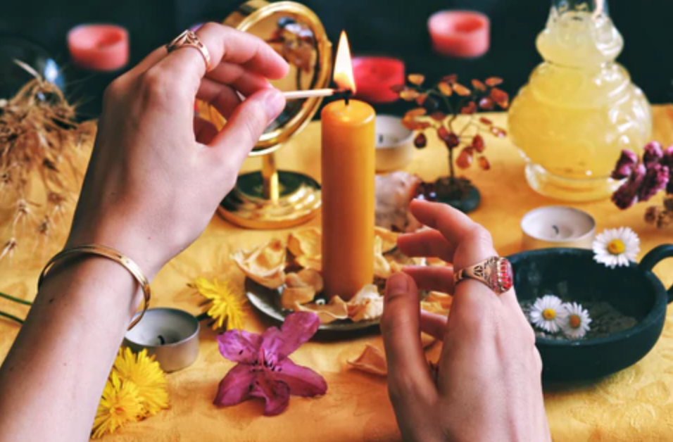 Woman's hands lighting a candle on a Litha altar